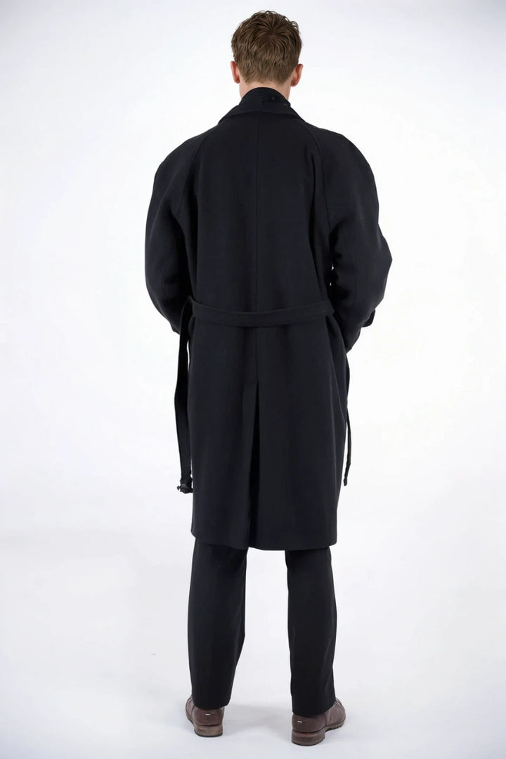 Men black overcoat walking through snowy streets, ideal for winter travel or city commuting.